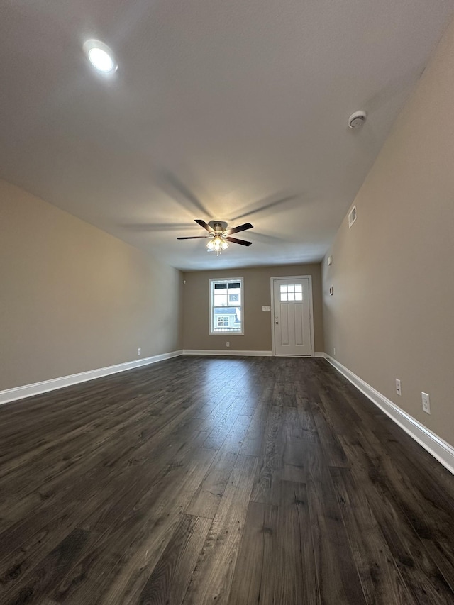 unfurnished living room with dark wood-style floors, a ceiling fan, visible vents, and baseboards