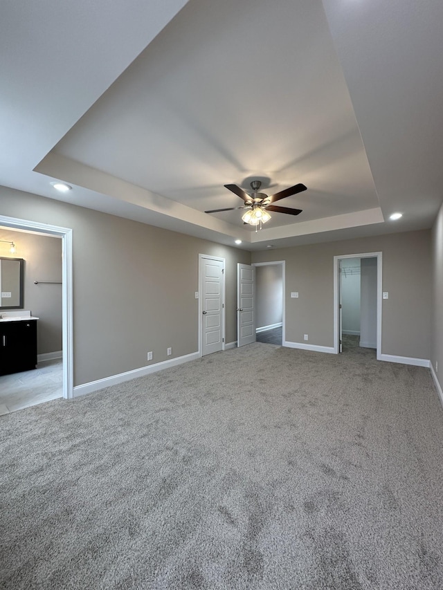 unfurnished bedroom with light carpet, baseboards, a raised ceiling, and recessed lighting