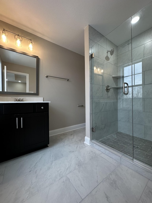 full bath with marble finish floor, a stall shower, vanity, and baseboards