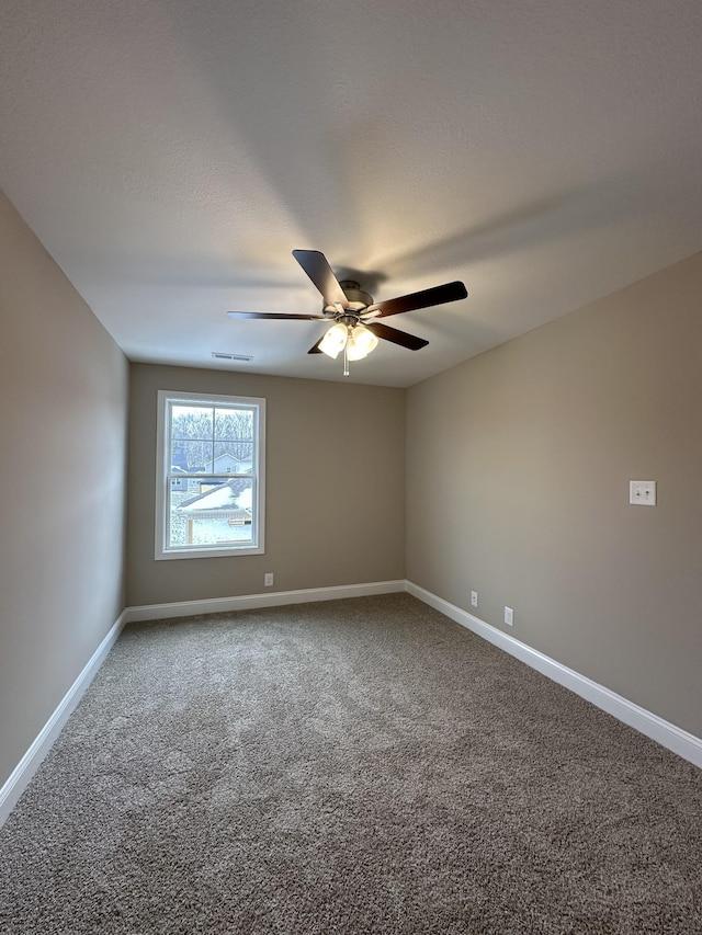 spare room with carpet floors, visible vents, ceiling fan, and baseboards