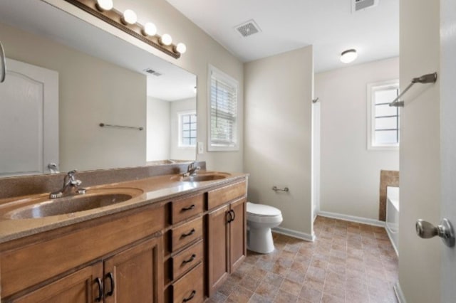 bathroom featuring toilet, vanity, and a bathing tub