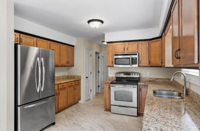 kitchen with stainless steel appliances, light stone counters, and sink