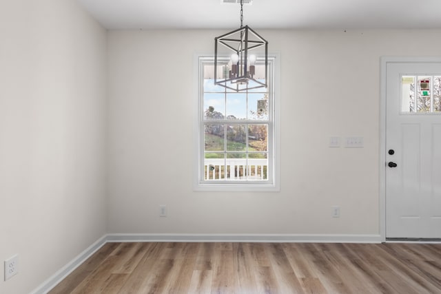 unfurnished dining area with hardwood / wood-style flooring and a notable chandelier