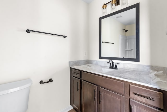 bathroom with walk in shower, vanity, and toilet