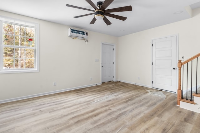 empty room featuring light wood-type flooring, a wall mounted AC, and ceiling fan