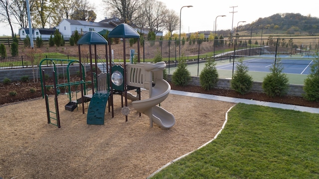 view of jungle gym with a lawn and tennis court