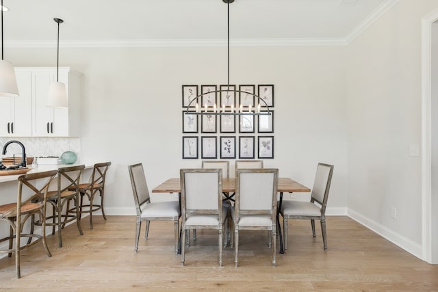 dining space featuring light hardwood / wood-style floors, sink, and crown molding