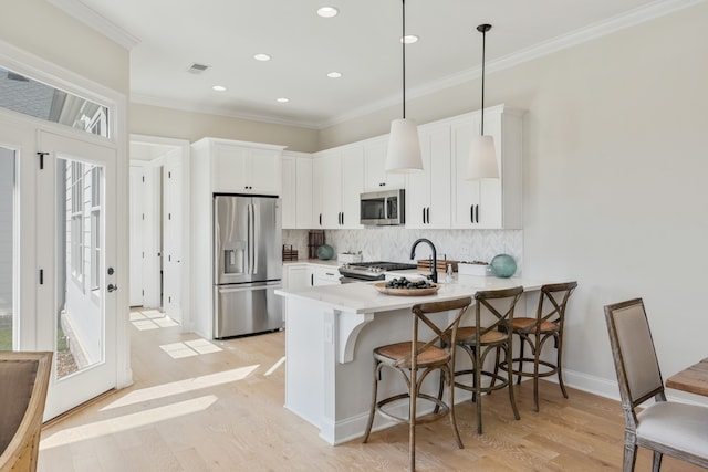 kitchen featuring light hardwood / wood-style floors, white cabinets, kitchen peninsula, hanging light fixtures, and stainless steel appliances