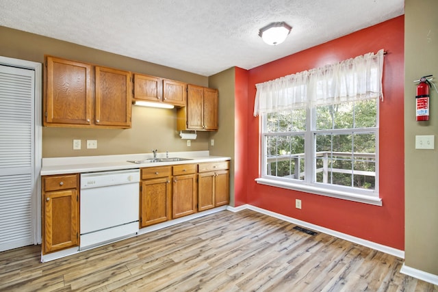 kitchen with a textured ceiling, sink, light wood-type flooring, and dishwasher