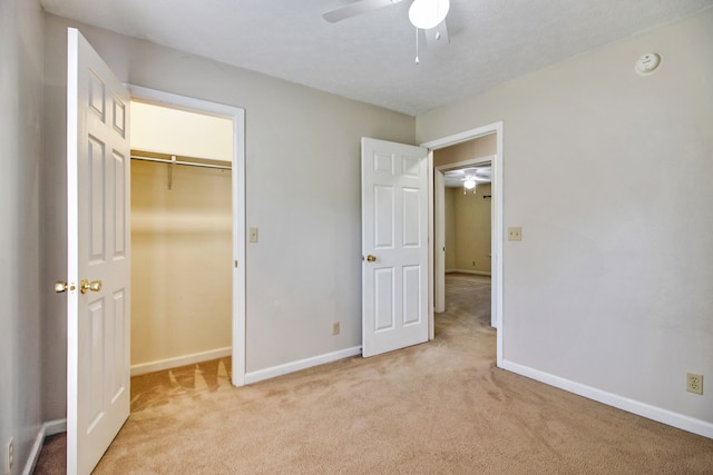 unfurnished bedroom with a spacious closet, light carpet, ceiling fan, and a closet