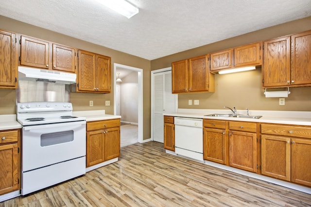 kitchen featuring white appliances, sink, light hardwood / wood-style floors, and a textured ceiling