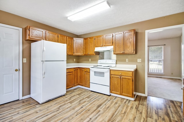 kitchen featuring light wood-type flooring, a textured ceiling, and white appliances