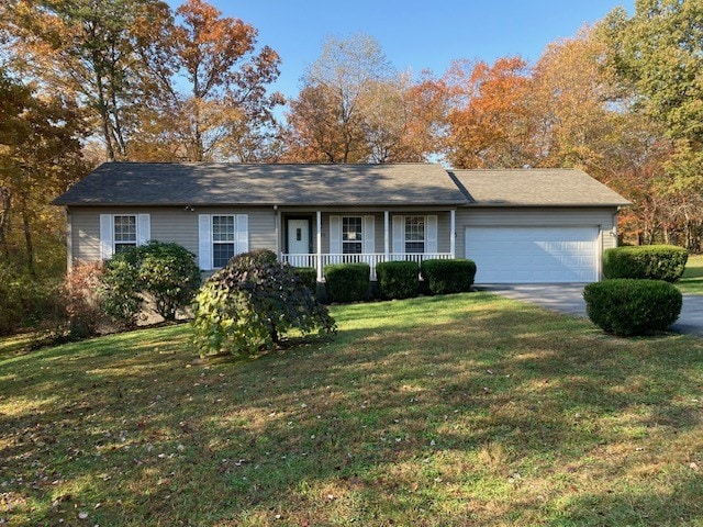 ranch-style home featuring a front lawn, a garage, and covered porch