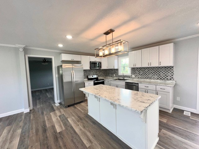 kitchen featuring pendant lighting, stainless steel appliances, white cabinetry, and a center island