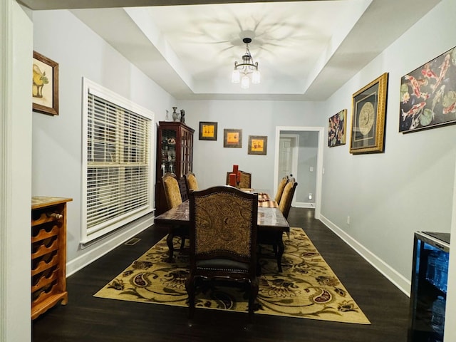 dining space featuring a notable chandelier, wine cooler, a tray ceiling, and dark wood-type flooring