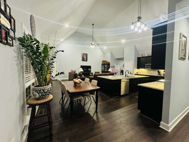 kitchen with a kitchen island with sink, hanging light fixtures, stainless steel appliances, backsplash, and dark hardwood / wood-style flooring