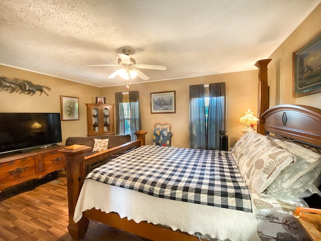 bedroom with ceiling fan, a textured ceiling, and hardwood / wood-style floors