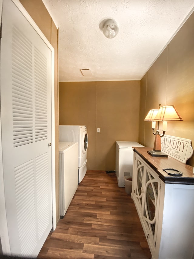 laundry room featuring a textured ceiling, separate washer and dryer, and dark hardwood / wood-style flooring