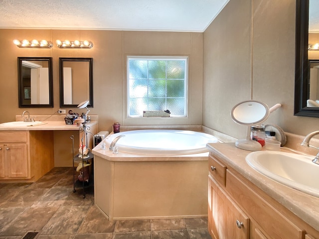 bathroom featuring a textured ceiling, vanity, and a bathing tub