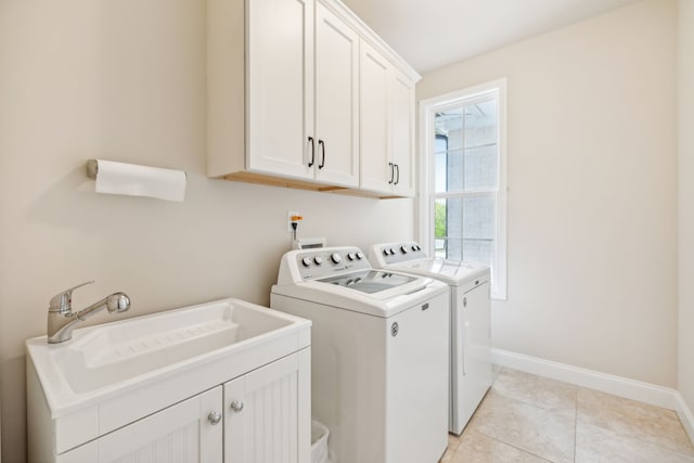 clothes washing area featuring washer and clothes dryer, cabinets, light tile patterned floors, and sink