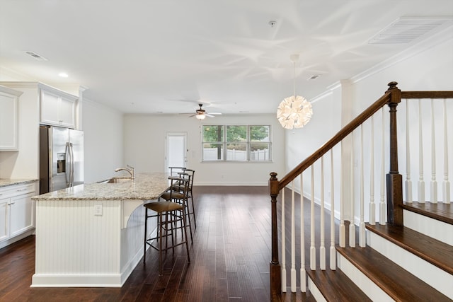 kitchen with light stone countertops, stainless steel refrigerator with ice dispenser, white cabinetry, and decorative light fixtures