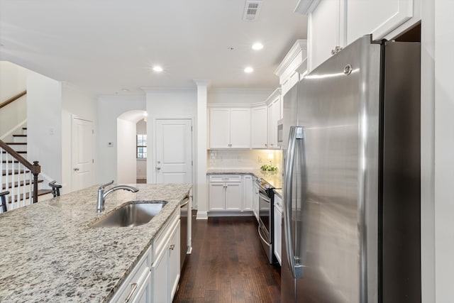 kitchen featuring appliances with stainless steel finishes, white cabinetry, light stone counters, dark hardwood / wood-style flooring, and sink