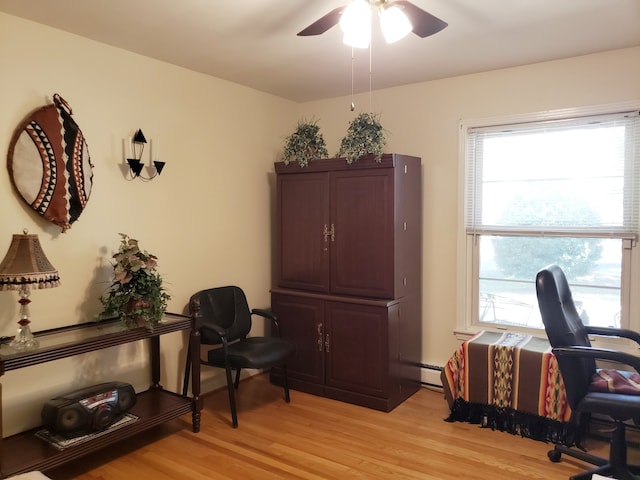 office area with light hardwood / wood-style floors, a baseboard heating unit, ceiling fan, and plenty of natural light