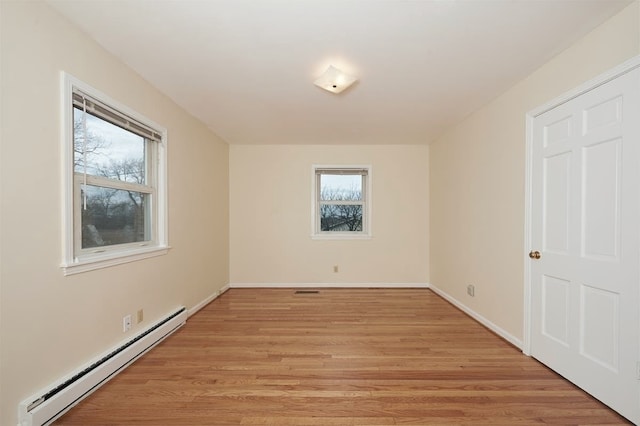 empty room with light hardwood / wood-style floors and a baseboard heating unit