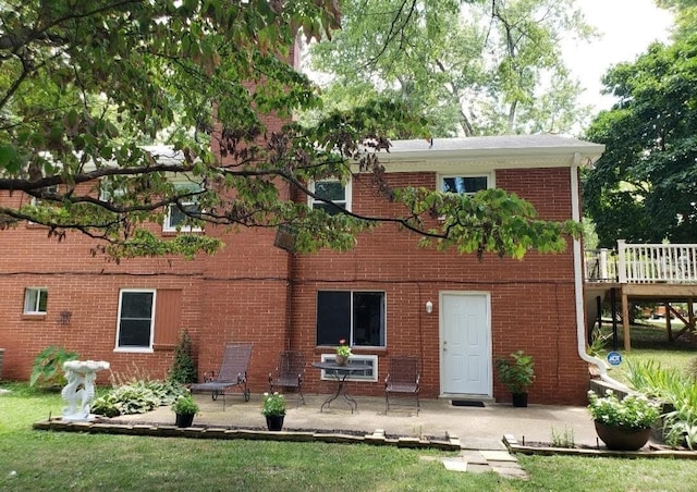 back of house with a wooden deck, a patio area, and a yard