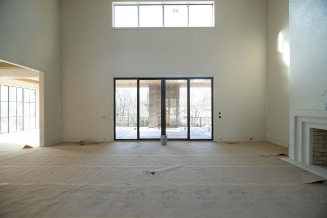 unfurnished living room featuring a towering ceiling