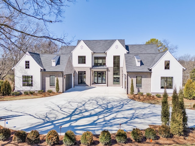 view of front of house featuring brick siding, driveway, and a shingled roof