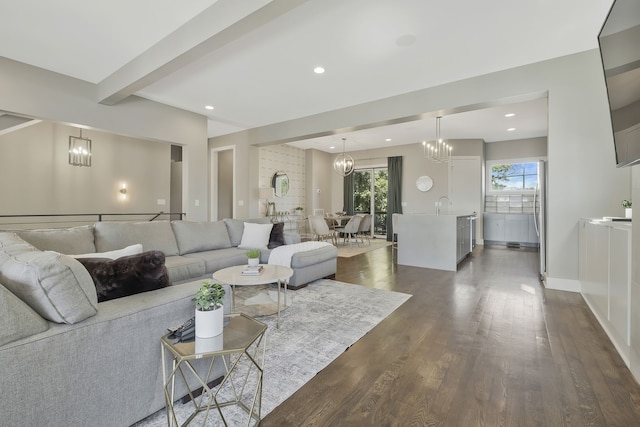 living room with an inviting chandelier, beam ceiling, dark wood-type flooring, and sink