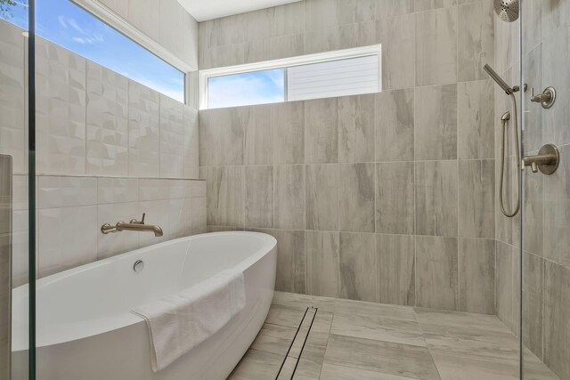 bathroom with tile walls and separate shower and tub