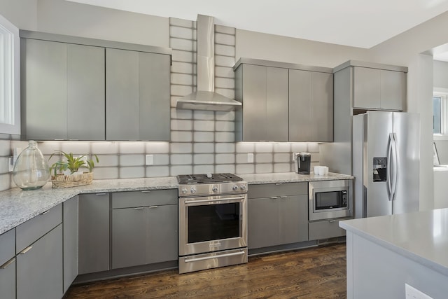 kitchen featuring gray cabinets, dark wood-type flooring, appliances with stainless steel finishes, and wall chimney exhaust hood