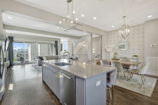 kitchen with dishwasher, dark wood-type flooring, sink, an island with sink, and decorative light fixtures