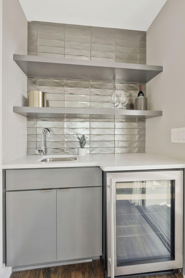 bar featuring gray cabinets, beverage cooler, dark wood-type flooring, and sink