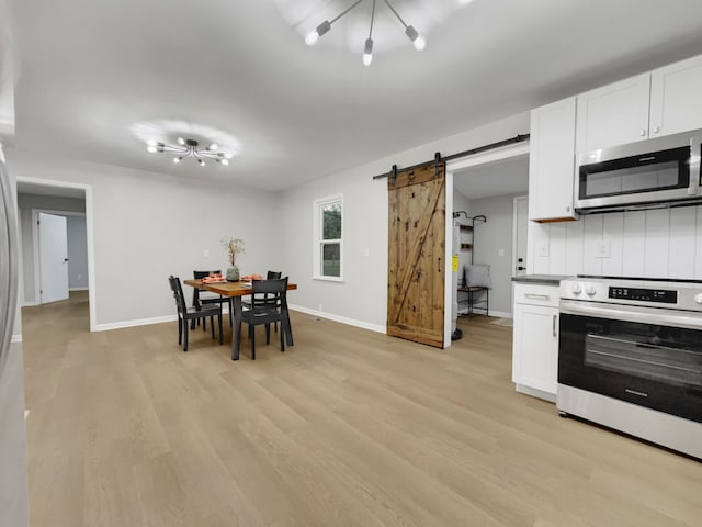 kitchen featuring a barn door, range, light hardwood / wood-style floors, and white cabinetry