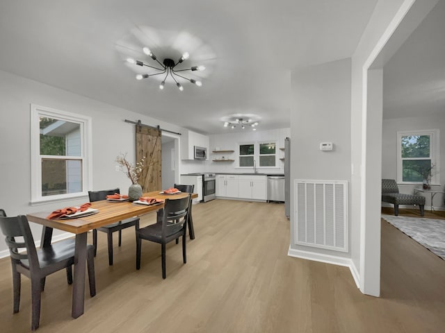 dining room featuring sink, light hardwood / wood-style floors, plenty of natural light, and a barn door