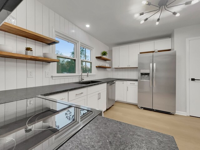 kitchen with light wood-type flooring, sink, stainless steel appliances, and white cabinets