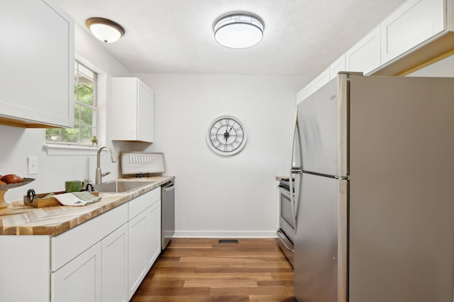 kitchen with light hardwood / wood-style flooring, white cabinets, appliances with stainless steel finishes, and sink