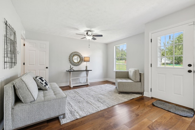 living room featuring wood-type flooring, a textured ceiling, ceiling fan, and a healthy amount of sunlight