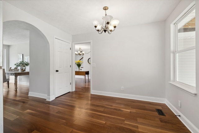 unfurnished dining area featuring a notable chandelier, dark hardwood / wood-style floors, and a textured ceiling