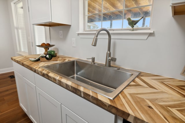 kitchen with white cabinetry, butcher block counters, and sink