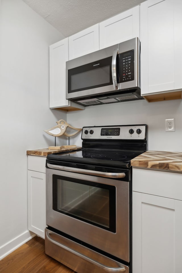 kitchen with a textured ceiling, dark wood-type flooring, stainless steel appliances, and white cabinets