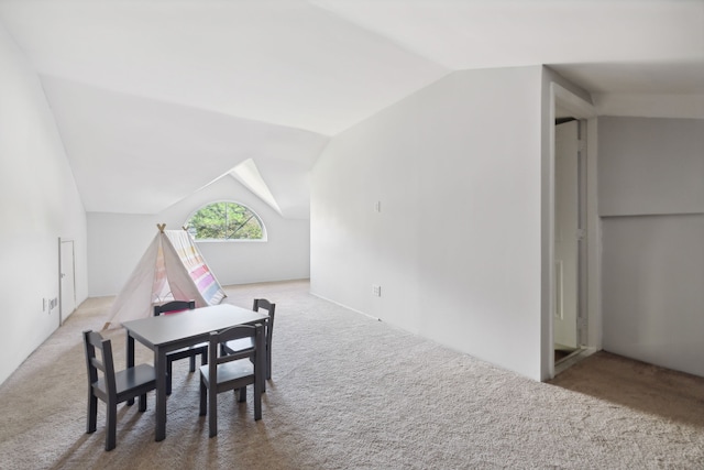 carpeted dining space featuring vaulted ceiling