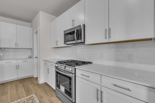 kitchen featuring light stone counters, white cabinets, light hardwood / wood-style flooring, stainless steel appliances, and backsplash