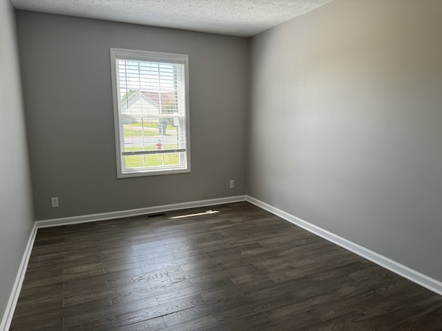 unfurnished room with a textured ceiling and dark hardwood / wood-style floors