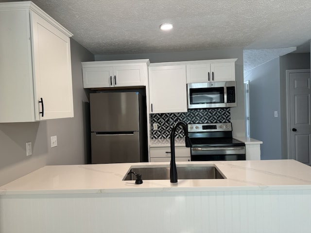 kitchen with stainless steel appliances, white cabinets, a textured ceiling, and sink