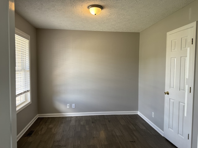 spare room with a textured ceiling, dark hardwood / wood-style flooring, and plenty of natural light