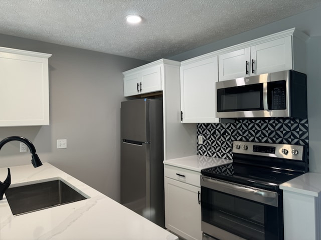 kitchen with white cabinets, a textured ceiling, appliances with stainless steel finishes, and sink